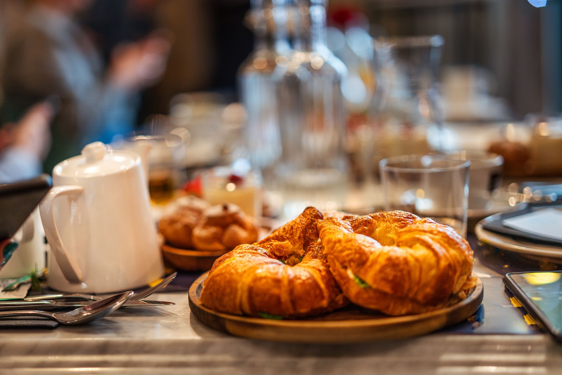 Close-up of croissants on a café table with elegant dining setting, perfect for breakfast.